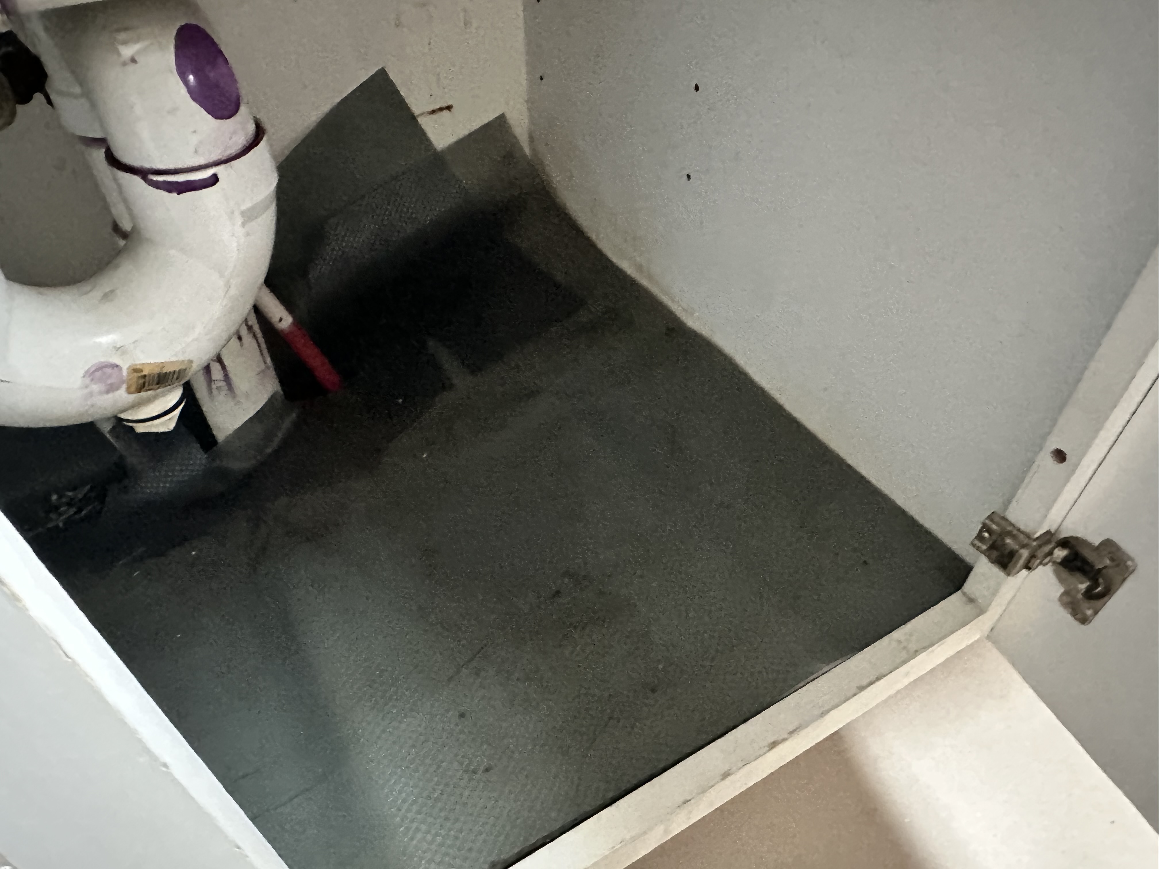 Damaged cabinet base and liner beneath the sink before restoration