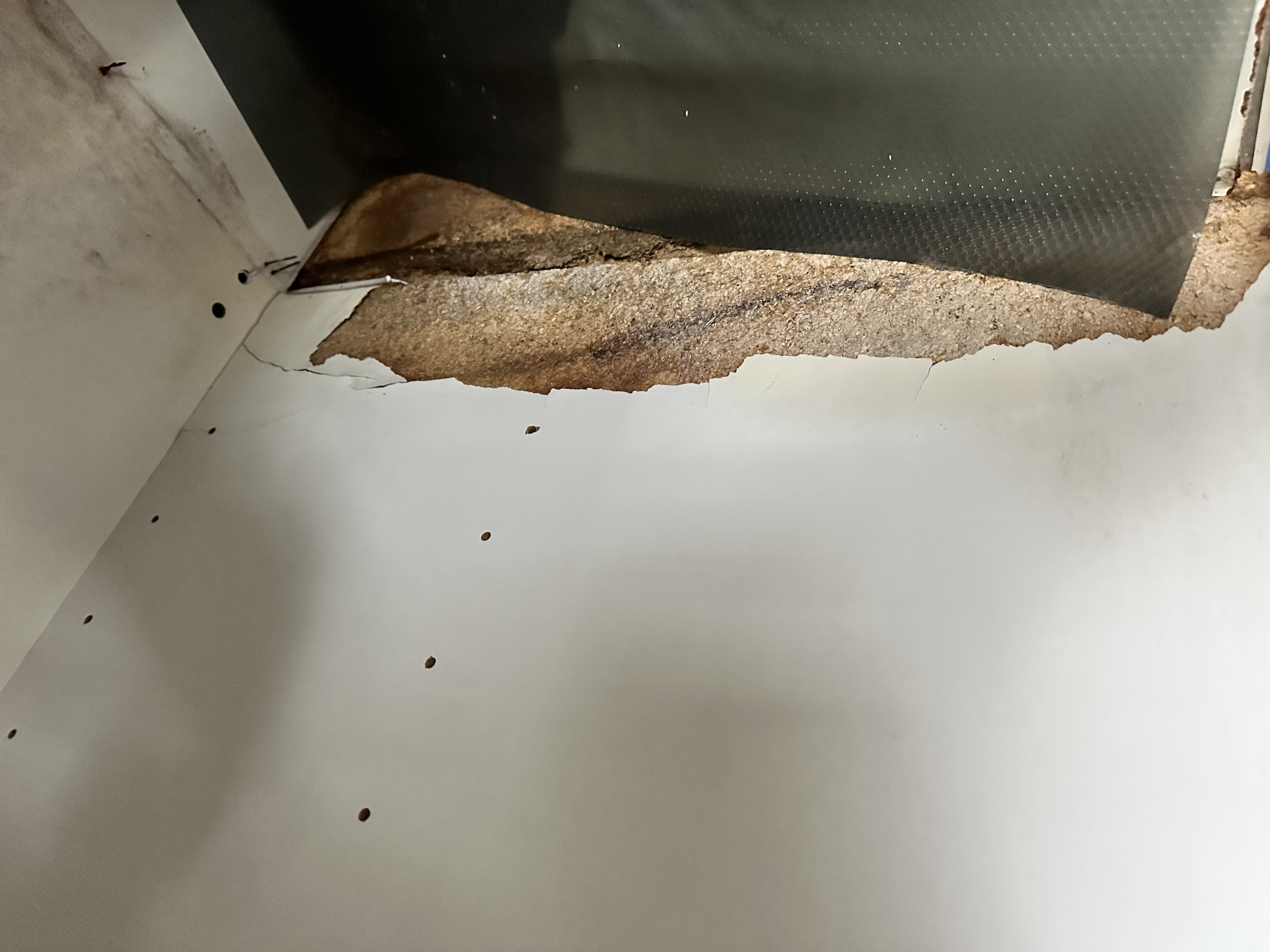 Exposed deteriorated cabinet material before repair
