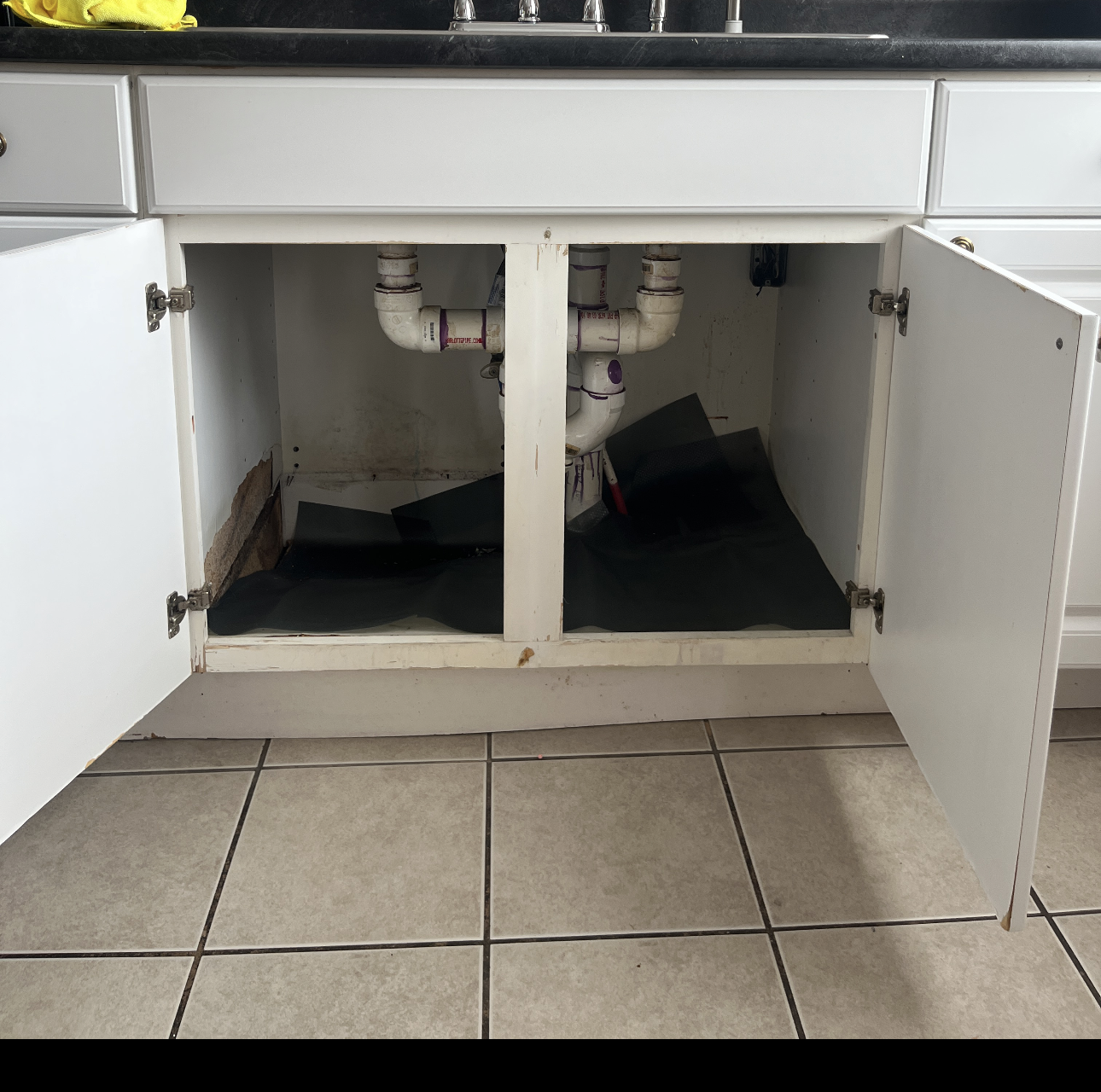 Water-damaged kitchen sink cabinet before repair